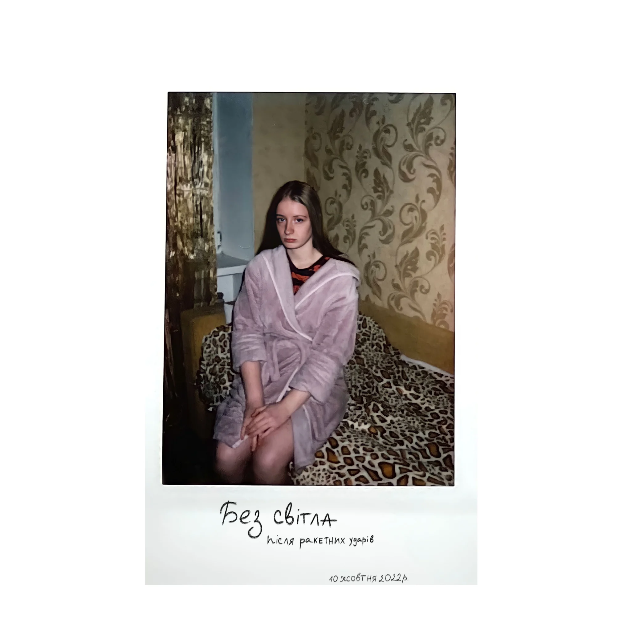 Polaroid of a young woman in a dressing gown, in a room with patterned wallpaper