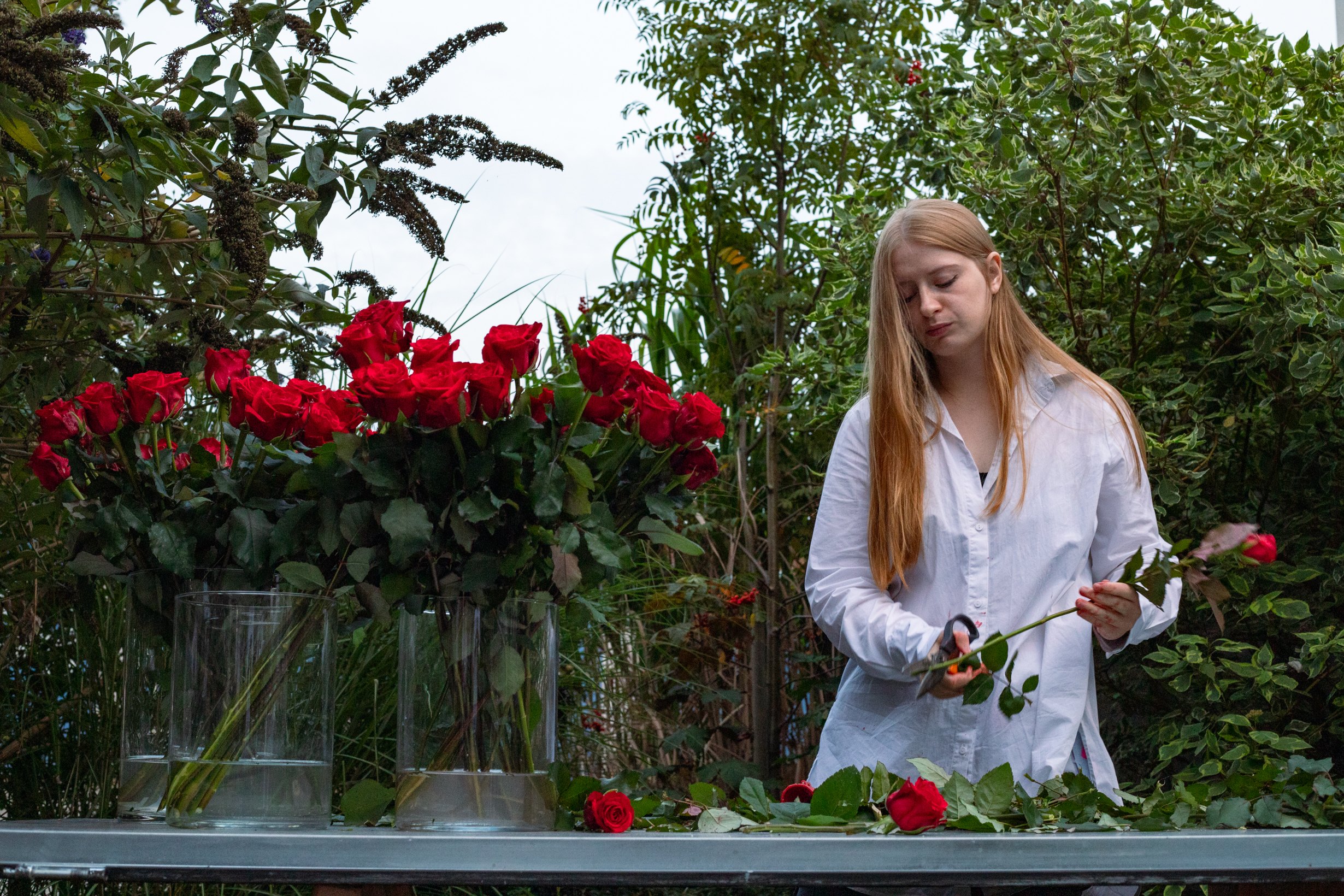The artist behind a table of red roses in the garden