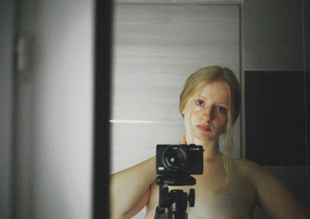 Self-portrait of the artist behind a camera on a tripod